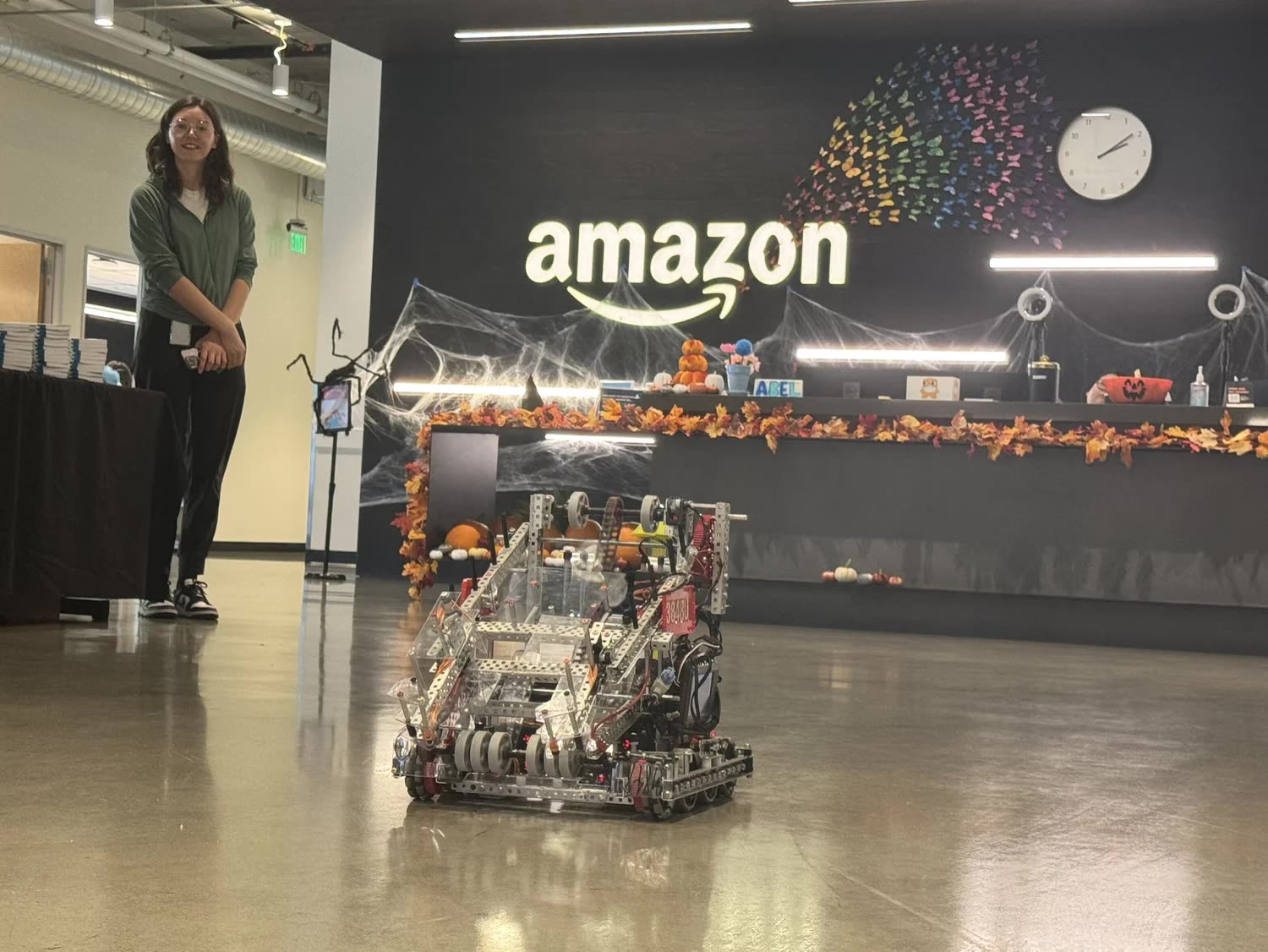 A VEX competition robot on the floor of an Amazon lobby beneath the Amazon wordmark