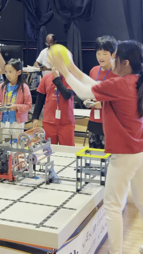 A team in red shirts loading a ball onto their robot at the field