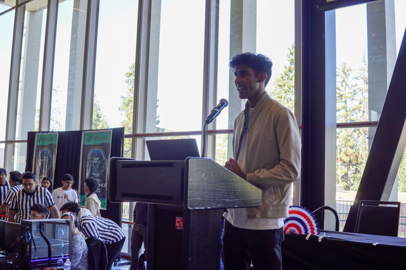Arya Sasikumar speaking from the podium at the opening of the One World Robotics Showcase at UC Berkeley