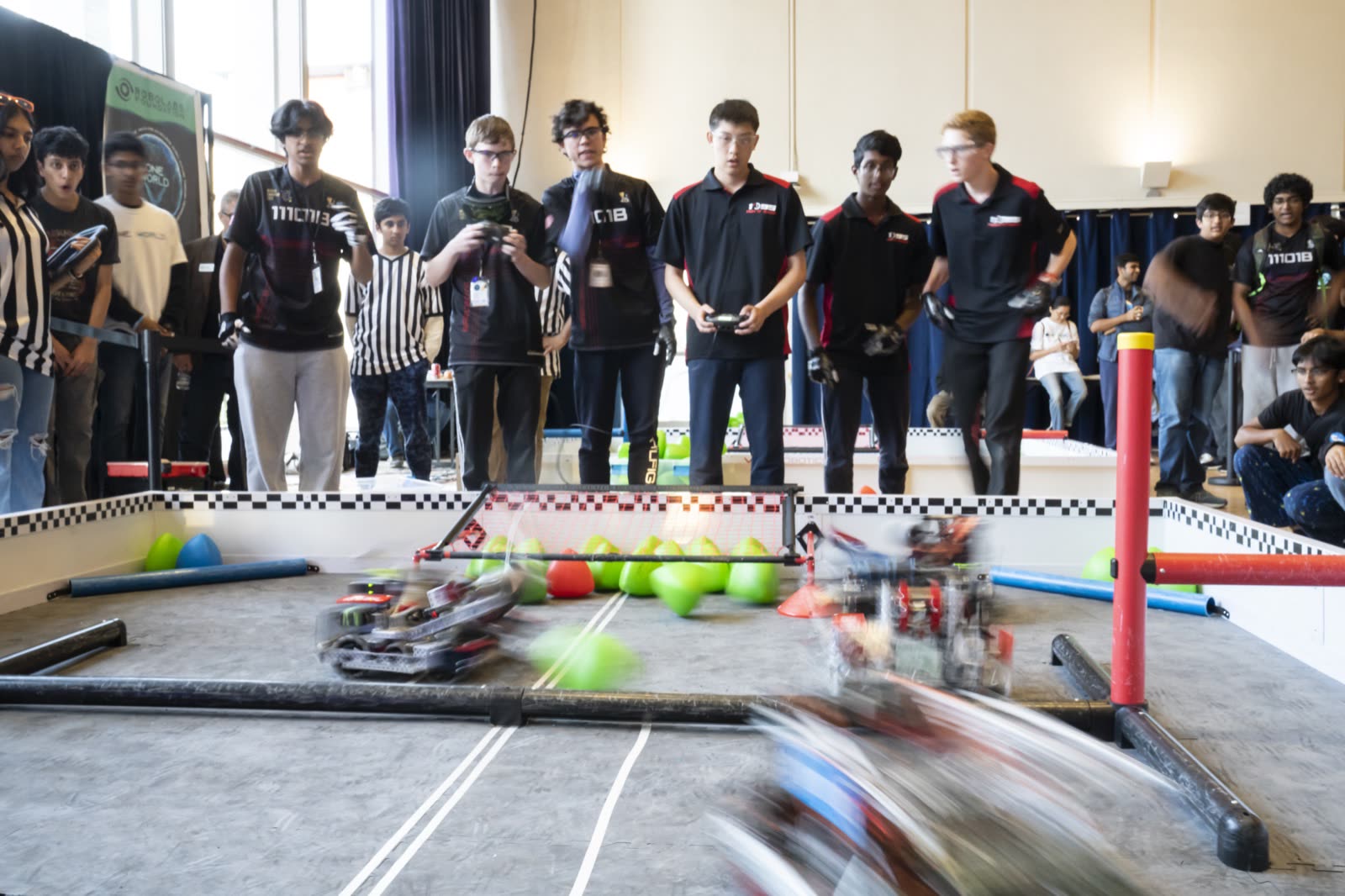 Motion-blurred robots during a qualification match with referees lined up behind