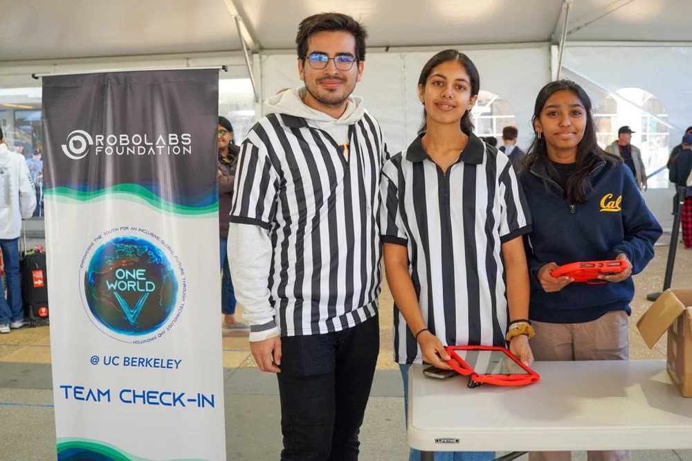 Three volunteers at the Robolabs Foundation team check-in banner