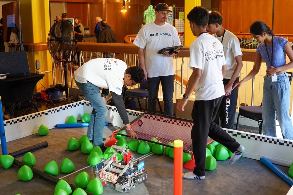 Volunteers in One World and Robolabs Volunteer shirts resetting the field between matches