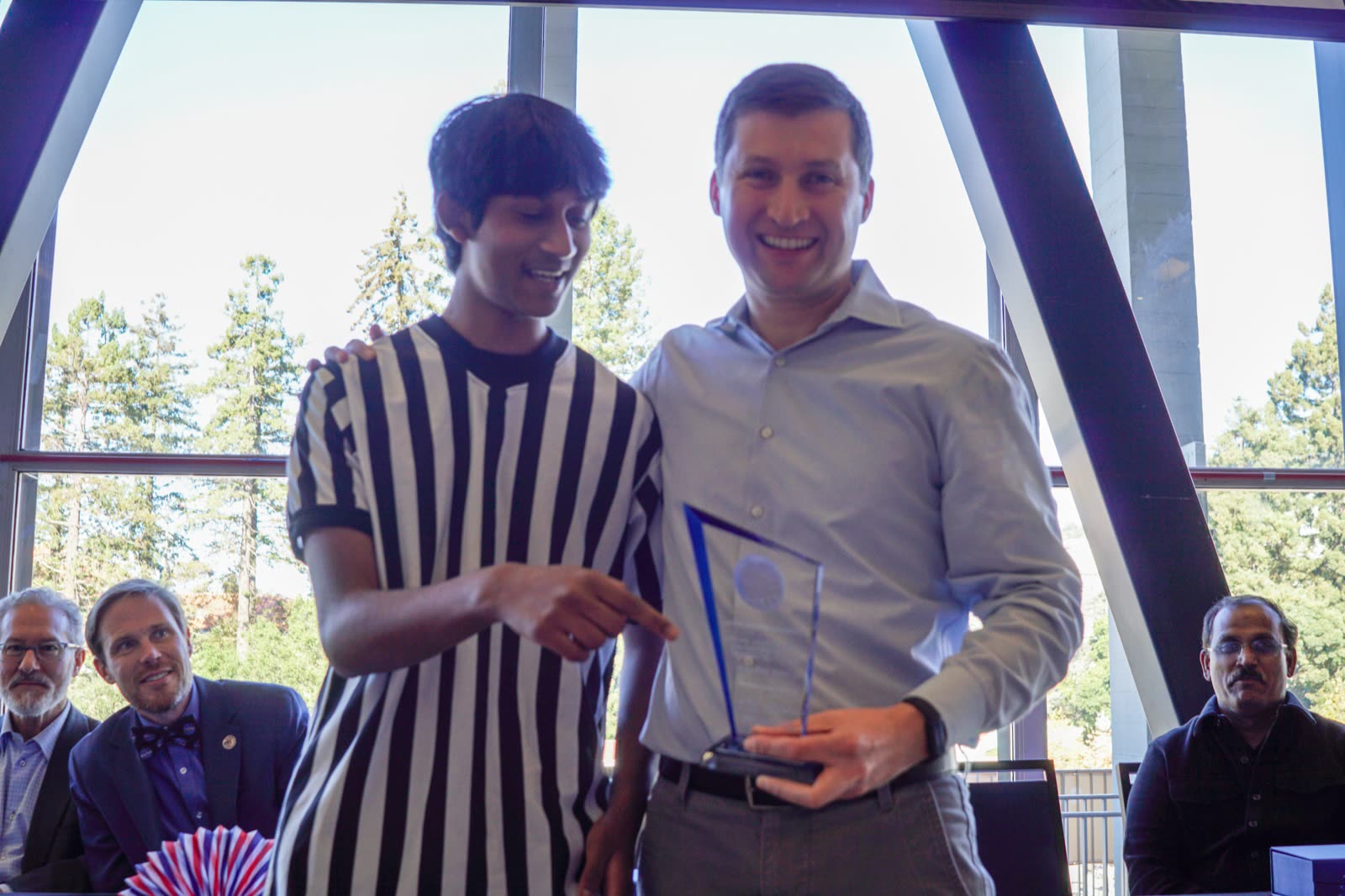Arya Sasikumar presenting a glass award to Omron Robotics CEO Olivier Welker