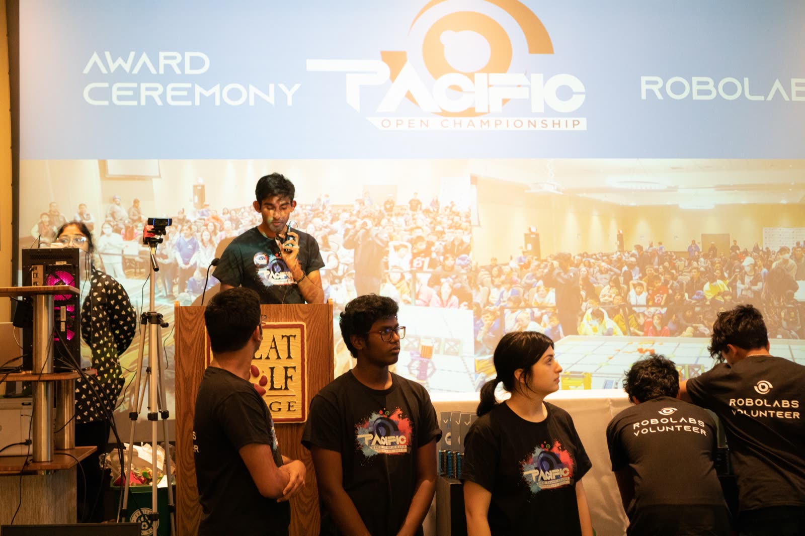 Arya Sasikumar at the podium during the Pacific Open Championship award ceremony with the volunteer crew