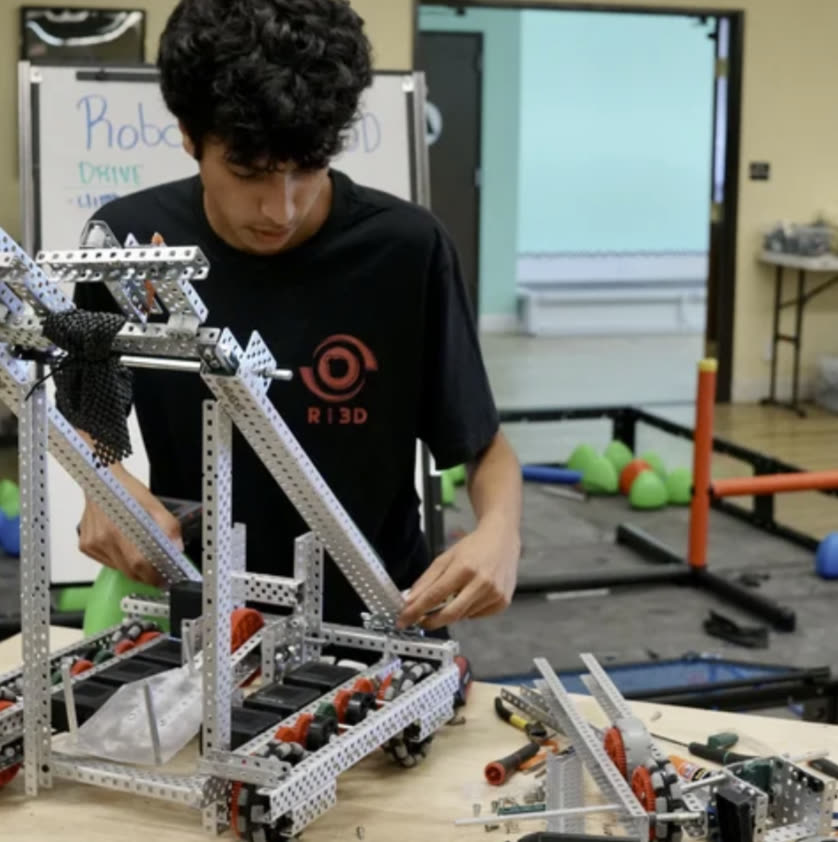 A student fitting a lift assembly onto the Ri3D robot